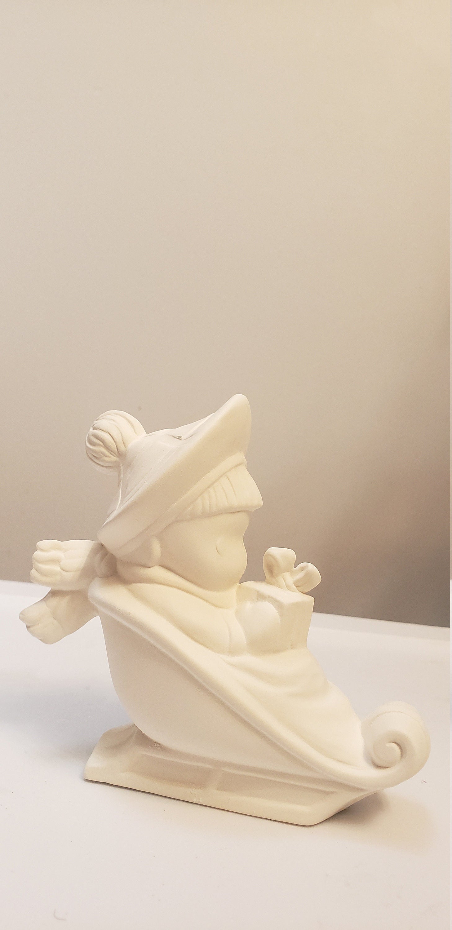 Boy on sled holding gift bisque