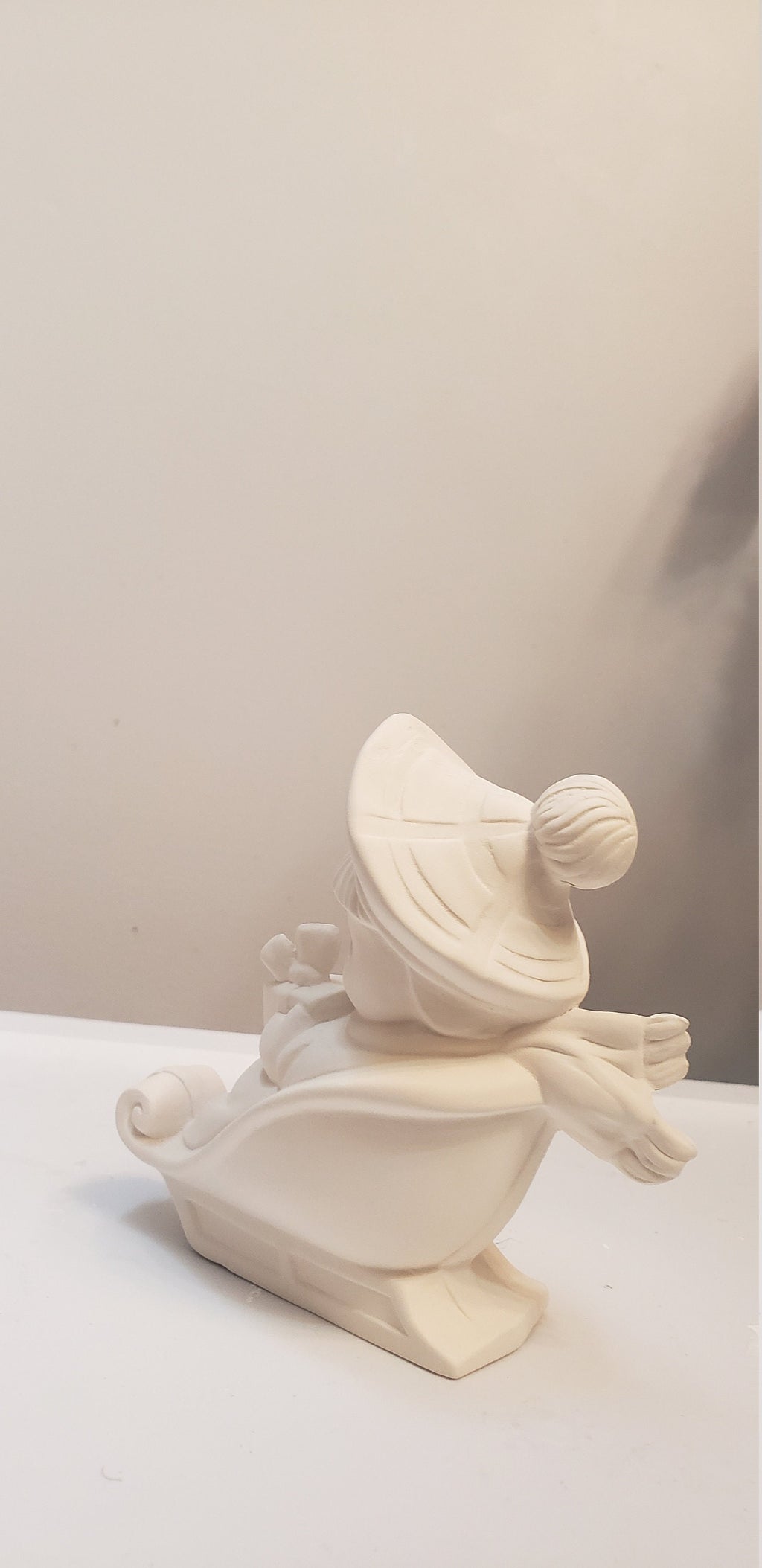 Boy on sled holding gift bisque