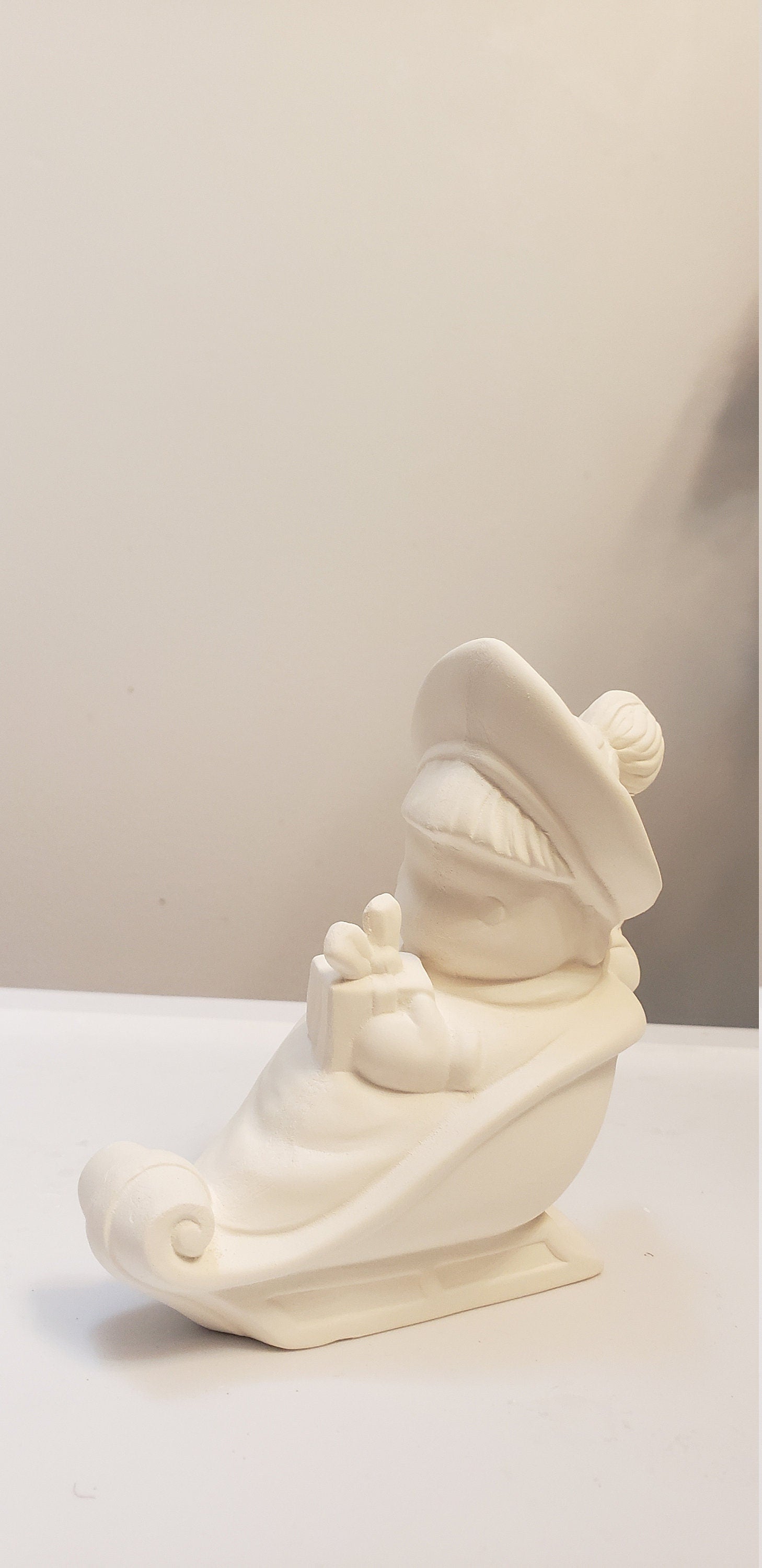 Boy on sled holding gift bisque